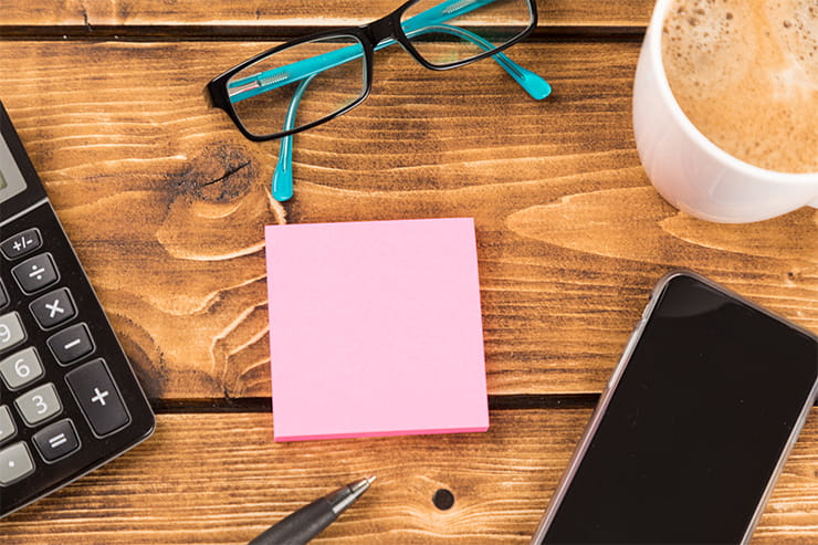 Desk with paper, pen, smartphone, glasses, coffee and calculator