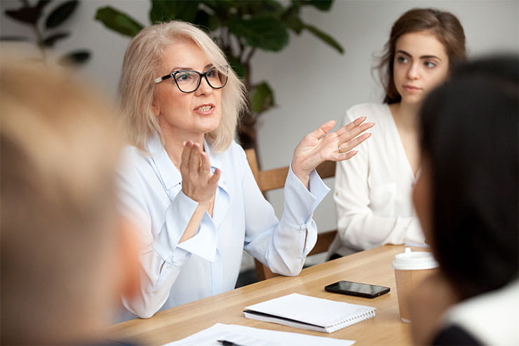 Woman speaking while seated at boardroom table.