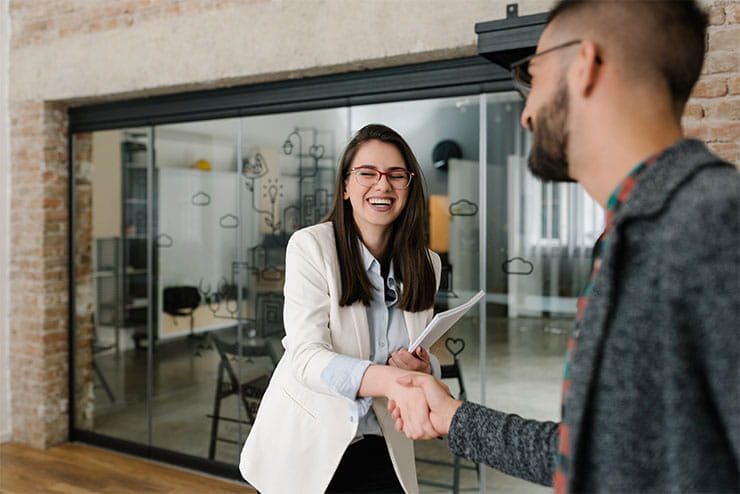 Two people shaking hands outside an office.