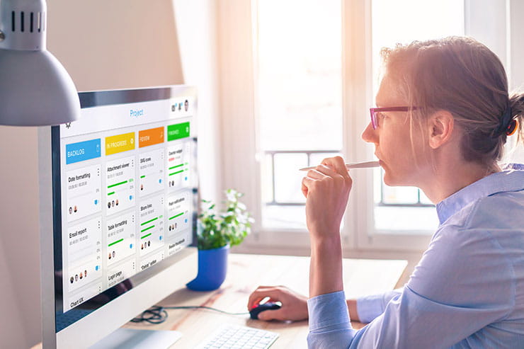Une professionnelle qui travaille à domicile gérant un projet d'équipe virtuelle à l'aide du logiciel kanban.
