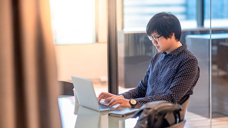 Post-coronavirus work life in Canada: Man with eye glasses working on laptop