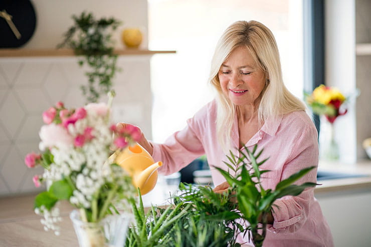 Femme qui arrose des plantes avec un arrosoir.